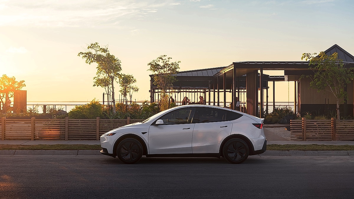 Tesla Model Y side profile parked near waterfront at sunset
